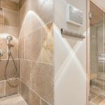 Shower with stone wall and glass wall to sauna