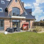 Haus mit Balkon, Garten und Liegestuhl im Freien.