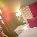 Schlafzimmer mit Bett, Nachttisch, Wandlampe und Stehlampe.