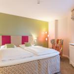 Schlafzimmer mit Doppelbett, Fenster und Sessel.