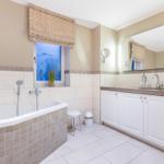 Badezimmer mit Badewanne, Waschbecken und Fenster mit Blick.