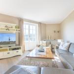 Wohnzimmer mit Sofa, Couchtisch und Fernseher. Fenster mit Blick aufs Meer.