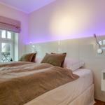 Bedroom with bed, window, and modern lighting.