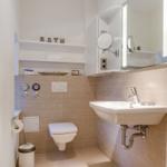 Bathroom with sink, toilet, and mirror cabinet.