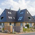 Modernes Haus mit dunklem Dach und Holzfassade. Terrasse und Gartenbereich.