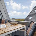 Terrasse mit Tisch und Stühlen. Blick auf Meer und Himmel.