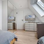 Schlafzimmer mit Dachschrägen, Fenster, Kleiderschrank und Bett.