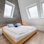 Schlafzimmer mit Doppelbett, zwei Fenstern und Textilwand