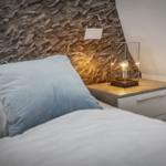 Schlafzimmer mit Bett, Nachttisch und Wandtapete mit Wellenmuster.