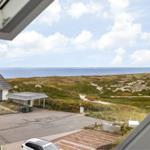Meerblick von einem Fenster, mit Strand und Dünen im Vordergrund.