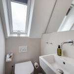 Badezimmer mit Dusche, Waschbecken und Toilette unter Dach