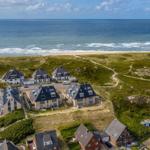 Strandnahe Häuser mit Grünflächen und Meerblick.