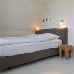 Schlafzimmer mit Bett, Nachttisch und Wandlampen.
