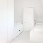 Zwei weiße Einzelbetten in einem Dachbodenzimmer mit weißen Schränken.