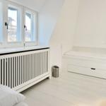Schlafzimmer mit weißem Bett, Fenster und Heizkörper