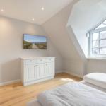 Schlafzimmer mit Dachschräge, Fenster und Bett.