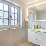 Badezimmer mit Waschbecken, Spiegel und Fenster. Wandfliesen und weiße Schrank.