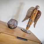 Holzengel mit Herzsymbol und Kerze auf einem Schrank