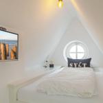Schlafzimmer mit Dachschrägen, Rundfenster und Wandbildschirm