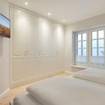 Schlafzimmer mit Bett, Kleiderschrank und TV an der Wand.