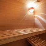 Sauna mit Holzbank und Wandbeleuchtung.