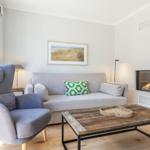Wohnzimmer mit Sofa, Sessel, Kamin und Holztisch.