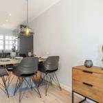 Esszimmer mit Holztisch, grauen Stühlen und moderner Hängelampe.