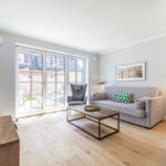 Wohnzimmer mit Sofa, Kamin und Glastür zum Garten.