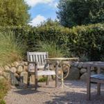 Garten mit zwei Holzstühlen und Tisch auf Kies