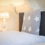 Schlafzimmer mit Bett, Kissen und Nachttischlampe unter Dachschrägen.