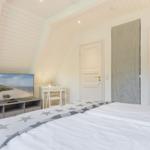 Schlafzimmer mit Dachschrägen, TV und Blick in Bad