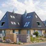 Moderne Ferienhaus mit dunklem Dach und Holzfassade. Terrasse und Gartenbereich.