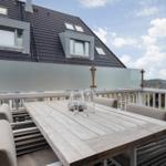 Terrasse mit Tisch und Stühlen, Blick auf Dach und Landschaft.