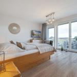 Schlafzimmer mit Bett, Fernseher und Balkonansicht.