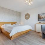 Schlafzimmer mit Bett, Nachttisch, Fernseher und Sessel.