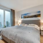 Schlafzimmer mit großem Bett, Fenster und Wandbild.