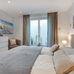 Schlafzimmer mit Bett, Schrank und Fenster zur Aussicht.