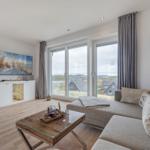 Wohnzimmer mit Sofa, Glas-Tisch und Blick auf die Landschaft.