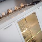 Weißer Schrank mit Gläsern und Kerzen auf der Oberfläche.