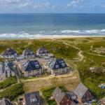 Meerfront-Villen auf grünen Dünen mit Blick auf den Strand.