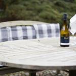 Holztisch mit Weinflasche und Gläsern im Garten