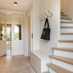 Eingangsbereich mit Treppe und Hakenwand. Schwarze Tasche hängt an der Wand.
