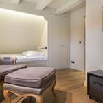 Schlafzimmer mit Bett, Stuhl und Fernseher an der Wand.