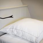 Schlafzimmer mit weißem Bett und Wandlampe.