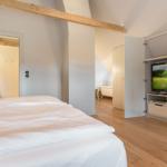 Schlafzimmer mit Doppelbett, TV und angrenzender Badewanne.