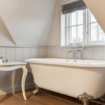 Bad mit freistehender Badewanne, Holzboden und Fenster mit Blick.