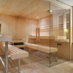 Sauna mit Holzbank und Glaswand. Fenster und Sitzbank im Vordergrund.