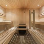 Holzsauna mit mehreren Sitzbänken und Heizung im Zentrum.