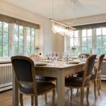 Esszimmer mit Holztisch, Stühlen und großen Fenstern.