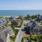 View of beach and houses with tiled and thatched roofs